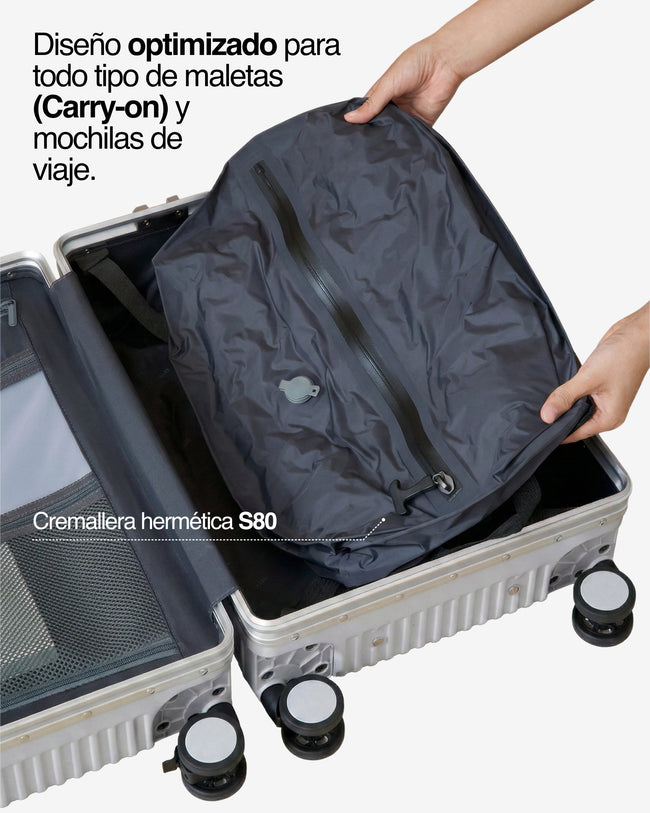 Manos colocando bolsa NVMA comprimida en maleta carry-on, destacando el ajuste optimizado y la cremallera hermética S80.